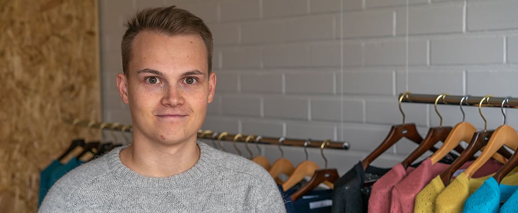 Alpa representative standing in front of a clothing rack