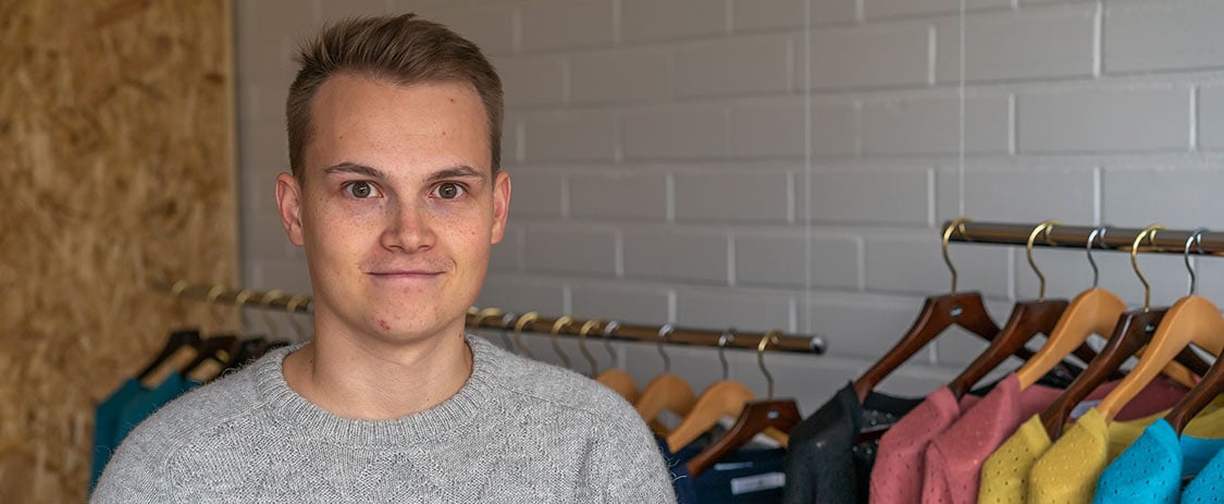 Alpa representative standing in front of a clothing rack