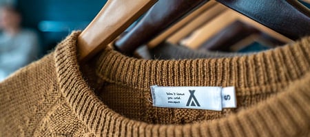 Alpa sweater on hanger, close-up of knit texture and label