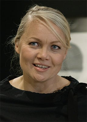 Salla Ahonen from Pentik, smiling in front of a dark background