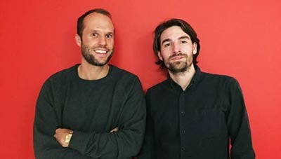 Two men from Scandinavian Luxury Group standing in front of a red background