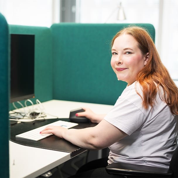Woman working at a desk and smiling at the camera