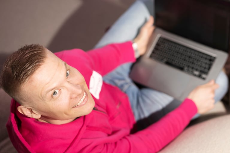 Man looking up at the camera while working on a laptop