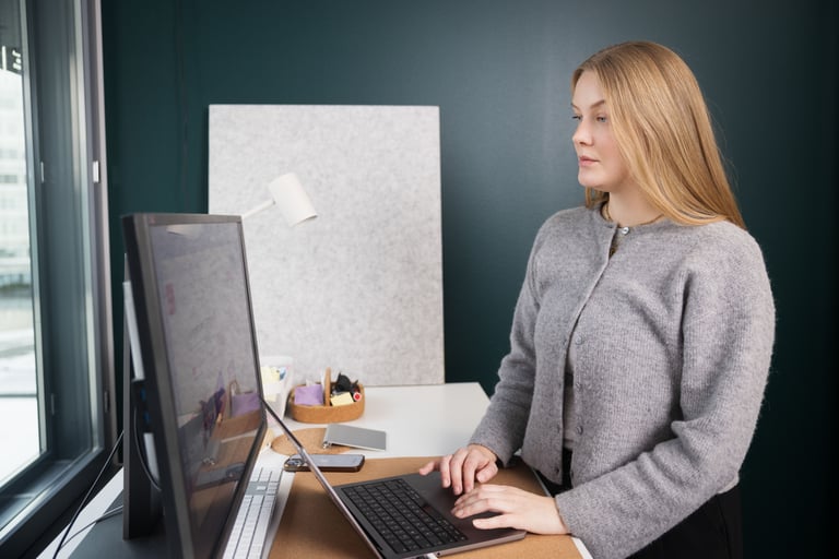 Woman working at a desktop computer by the window