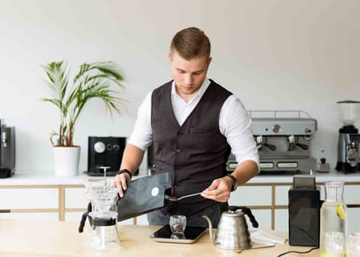Man brewing pour-over coffee in a modern café setting
